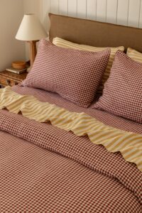 Close shot of a bed, styled with Pinot Gingham and Yellow Stripe bed linen.