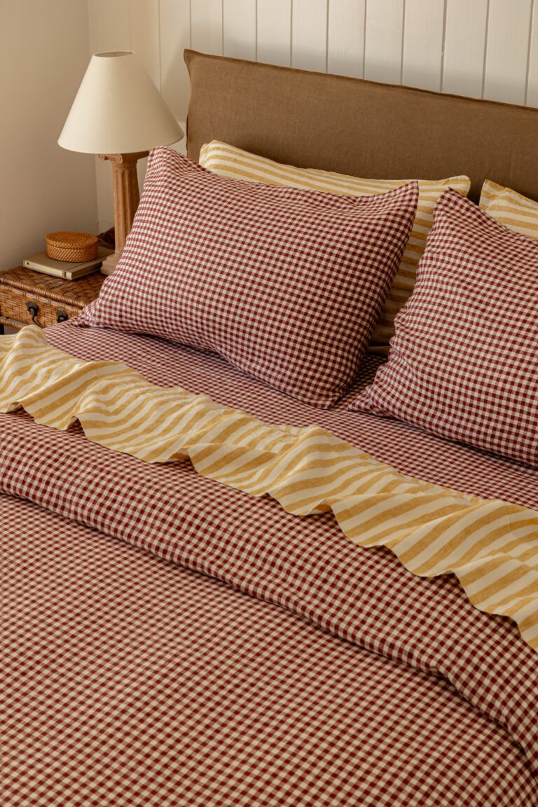Aerial shot of gingham and yellow striped sheets on a bed.