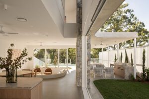 Modern architectural open plan living that opens up to an outdoor entertaining area, featuring natural light, concrete, and stonework.
