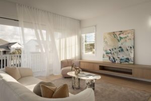 A light filled modern living room with marble coffee table, large abstract art, and muted dusky pink tones.