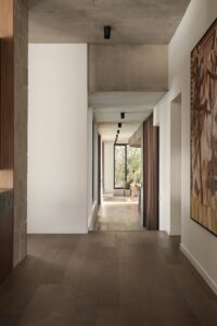 Looking down the hall from the entrance down to the kitchen and living with artwork on the right hand wall.