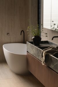 Bath in bathroom with marble top vanity and vase with greenery.
