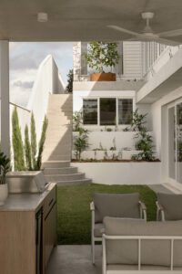 A modern and architectural outdoor entertaining area featuring tiered gardens and a built in barbecue.