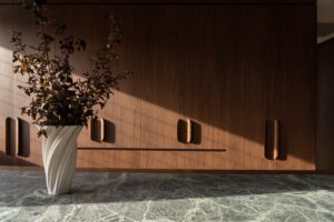 Walnut wardrobe cabinetry with an island marble top bench with a vase and greenery.