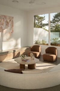 A modern and architectural living room featuring a sunken lounge and marble coffee table with tulips and ceramic vases.