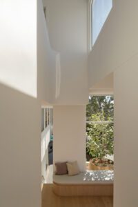 A modern and light-filled home with a built in bench seat and decorative throw cushions.