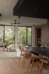 View from dining room down to sunken lounge room. Black dining table with walnut chairs.