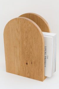 An arch shaped magazine rack made from oak.