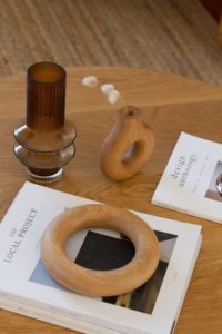 A vase and objects decorate an oak coffee table.