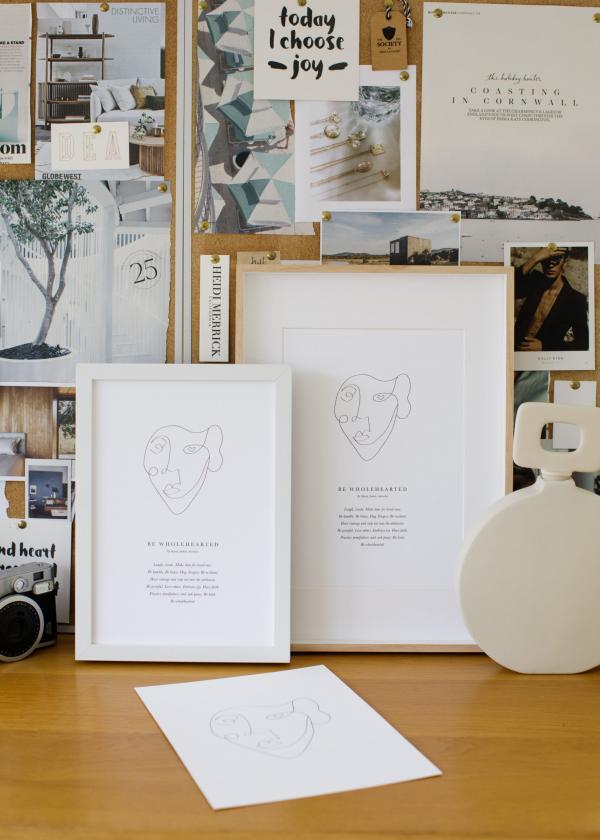 A Be Wholehearted Mantra Print in an oak frame on a desk.