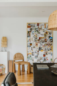 A ceiling-high collaged inspiration board sits in a modern studio office next to a Rachel Donath chair.
