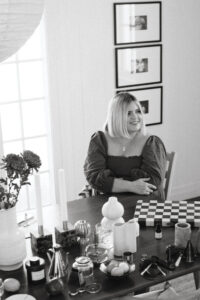 A black and white photo of Hayley sitting at her dining table during a shoot.