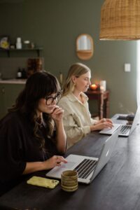 Two women sitting at a desk in a studio at their apple Mac computers.