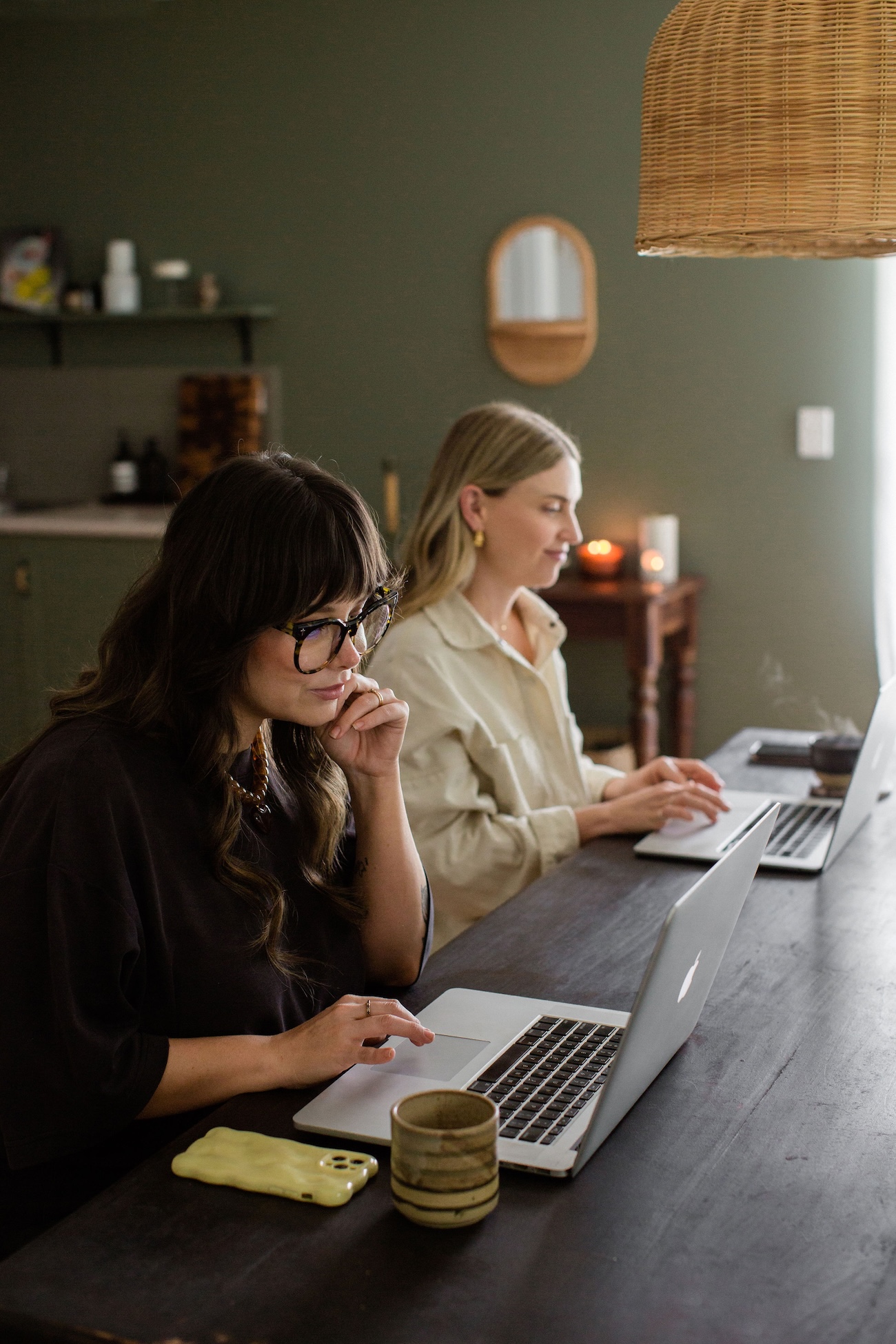 Two women sitting at a desk in a studio at their apple Mac computers.
