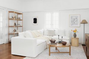 A living room with a new white lounge, oak coffee table, artwork and a lamp.