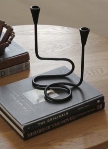 A candle holder on a coffee table and stack of books.