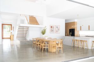 A modern dining room and kitchen with concrete floors.