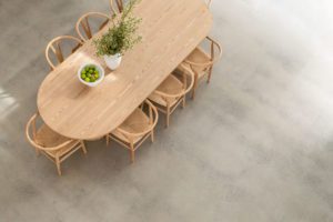 A modern dining room with a curved oak dining table and wishbone chairs.