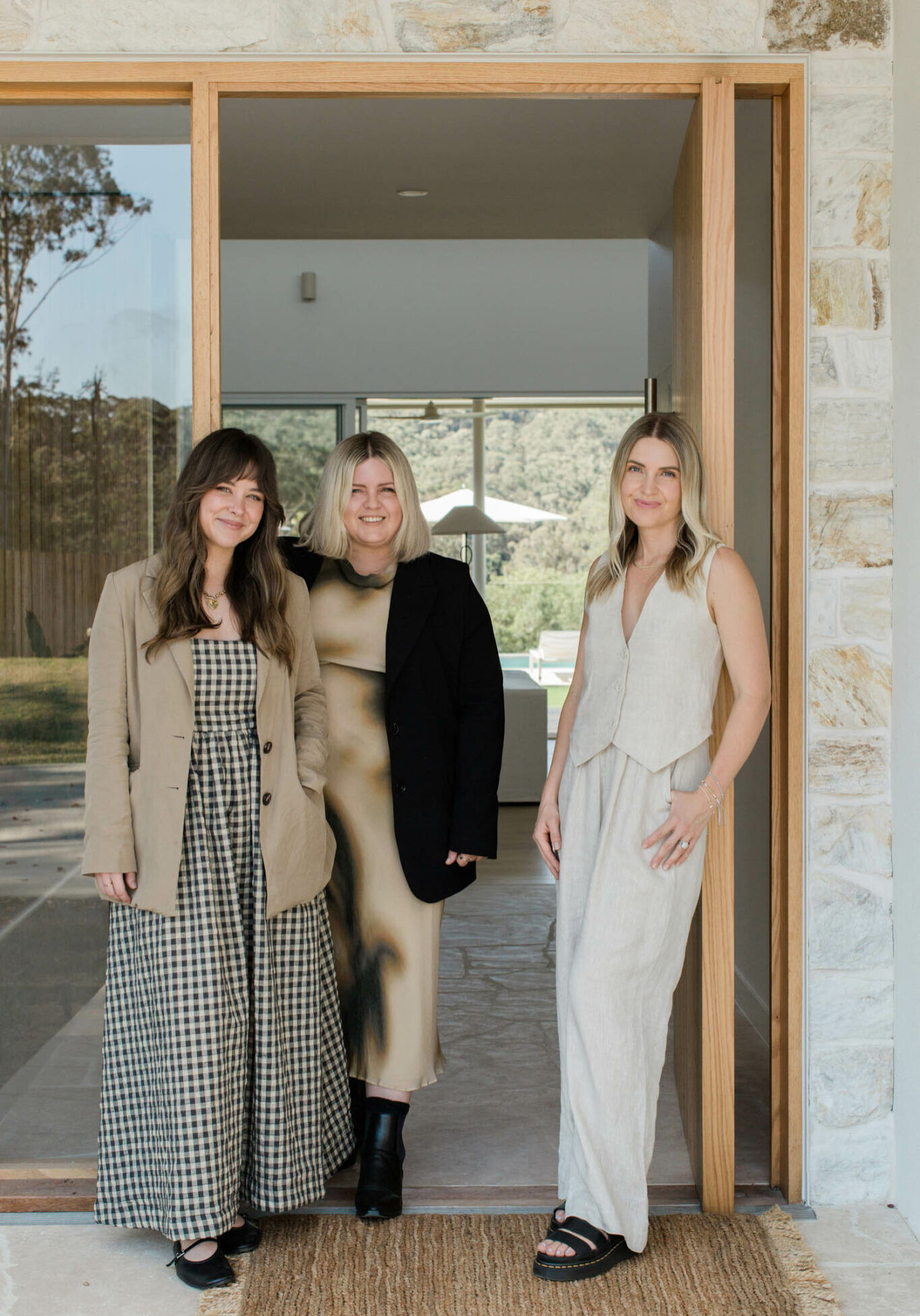 Three women standing in a doorway with a stone detailed entrance.