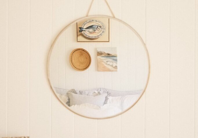 Primary bedroom of a country style Queenslander home displayed in the reflection of a circular mirror.