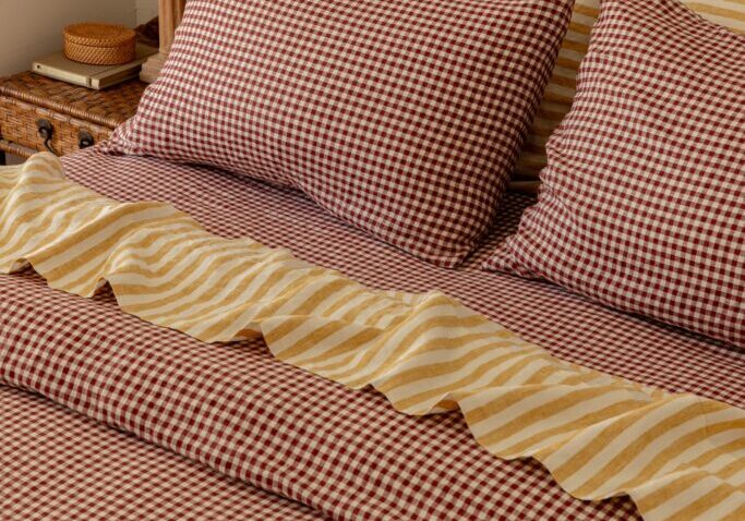 Aerial shot of gingham and yellow striped sheets on a bed.